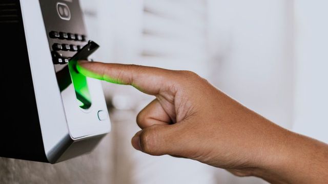 A person is using a fingerprint scanner to access a door.