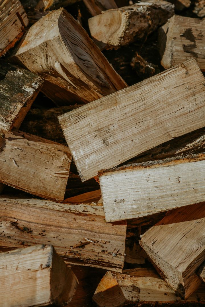 Stacked split firewood logs in shades of brown and tan.