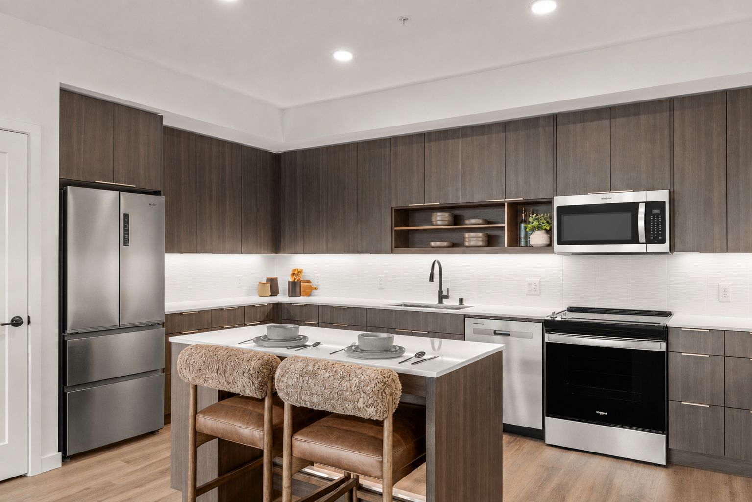 Modern kitchen with stainless appliances, gray cabinets, island seating, and hardwood floors