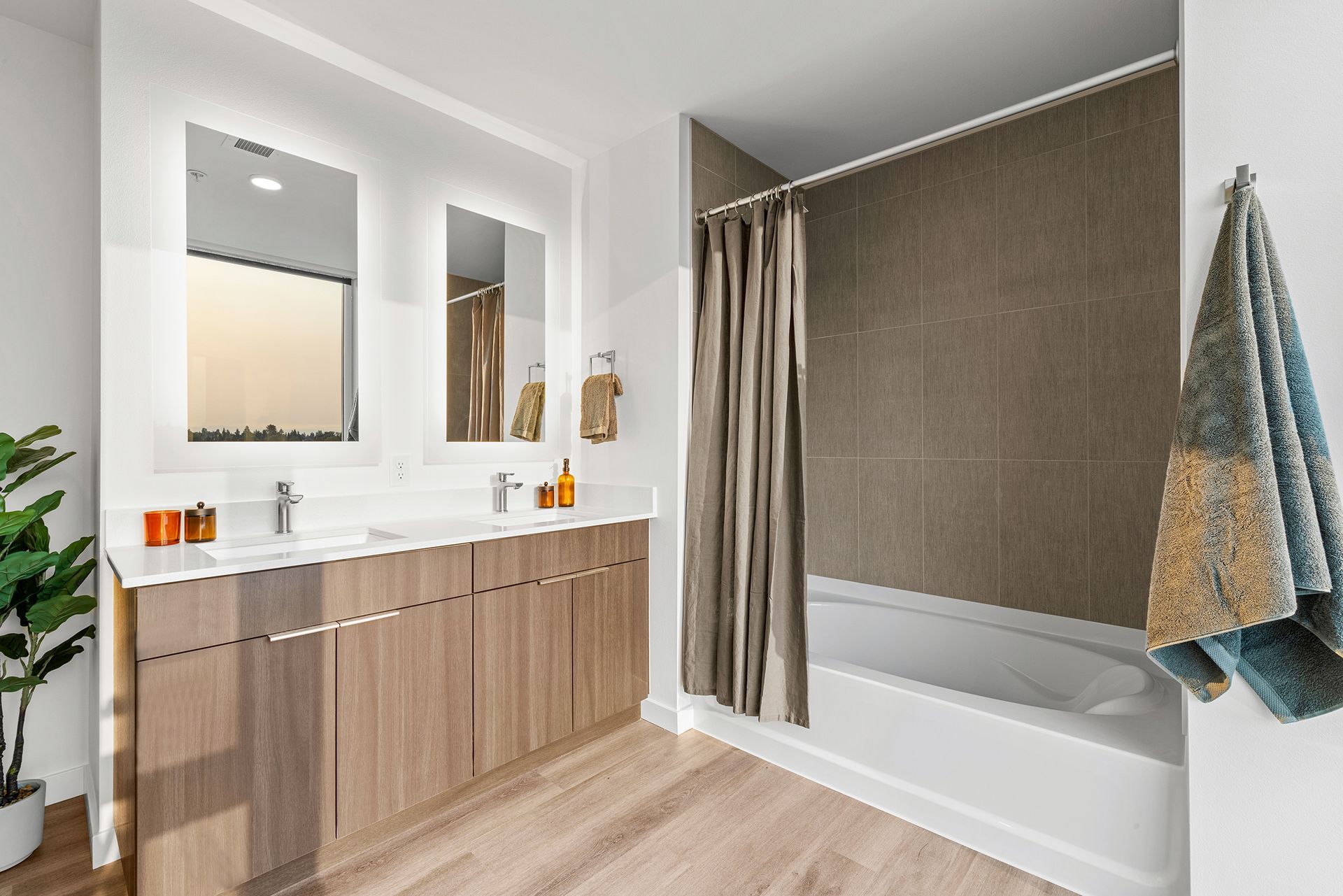Modern bathroom with wood vanity, large mirror, and a bathtub with beige curtain and towels