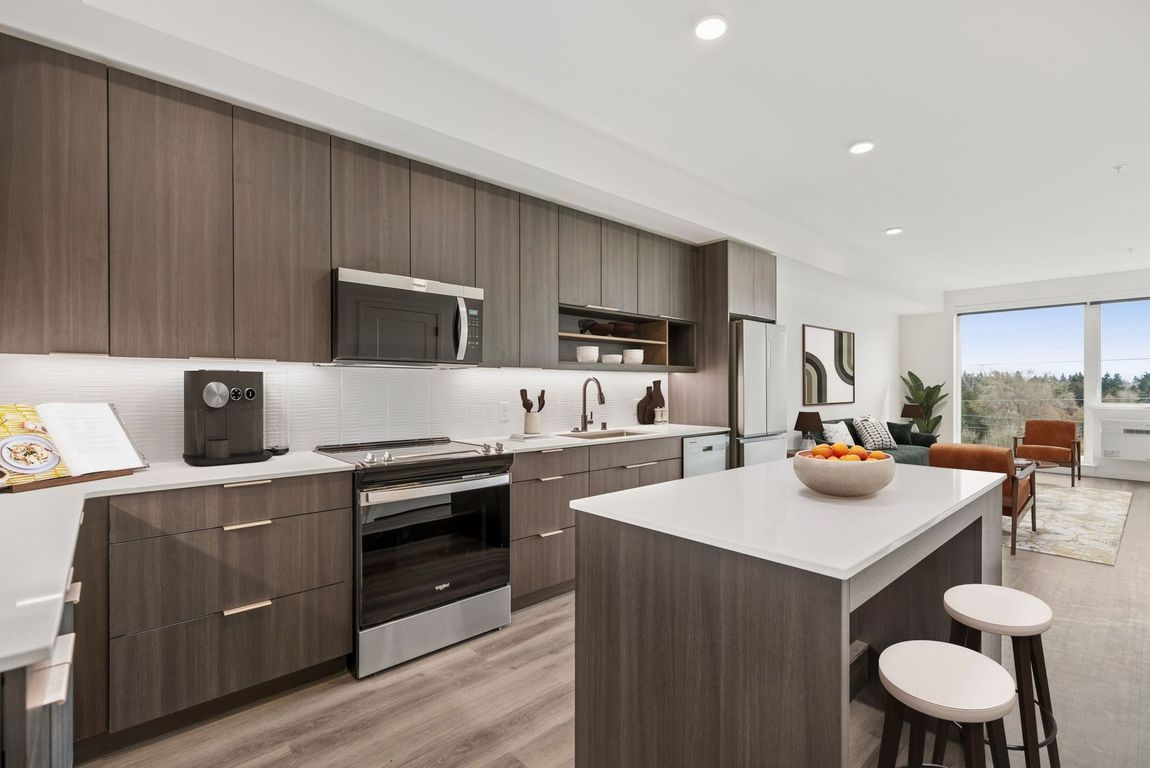 Modern kitchen with dark wood cabinets, white island, and large windows overlooking a patio