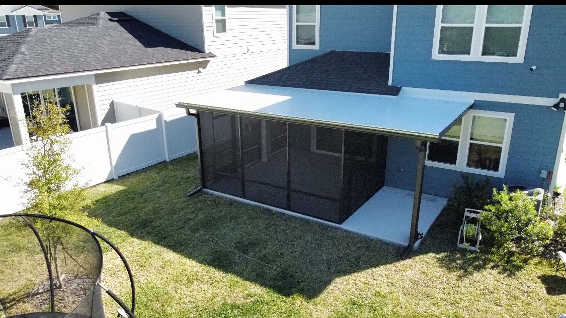 Backyard with a screened porch attached to a blue house, white fence, and grassy yard.