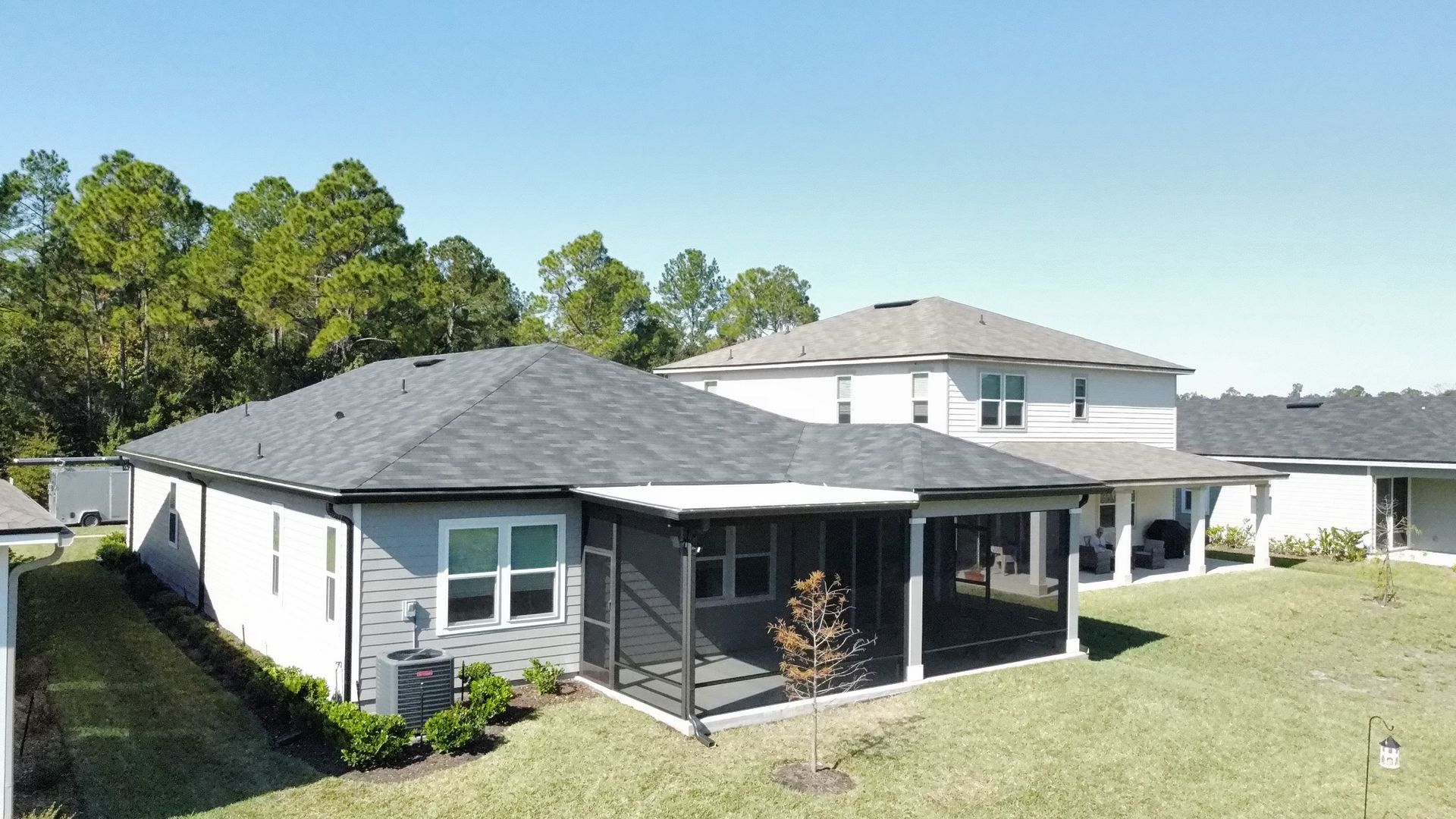 Single-story white house with gray roof and covered patio in a sunny suburban yard