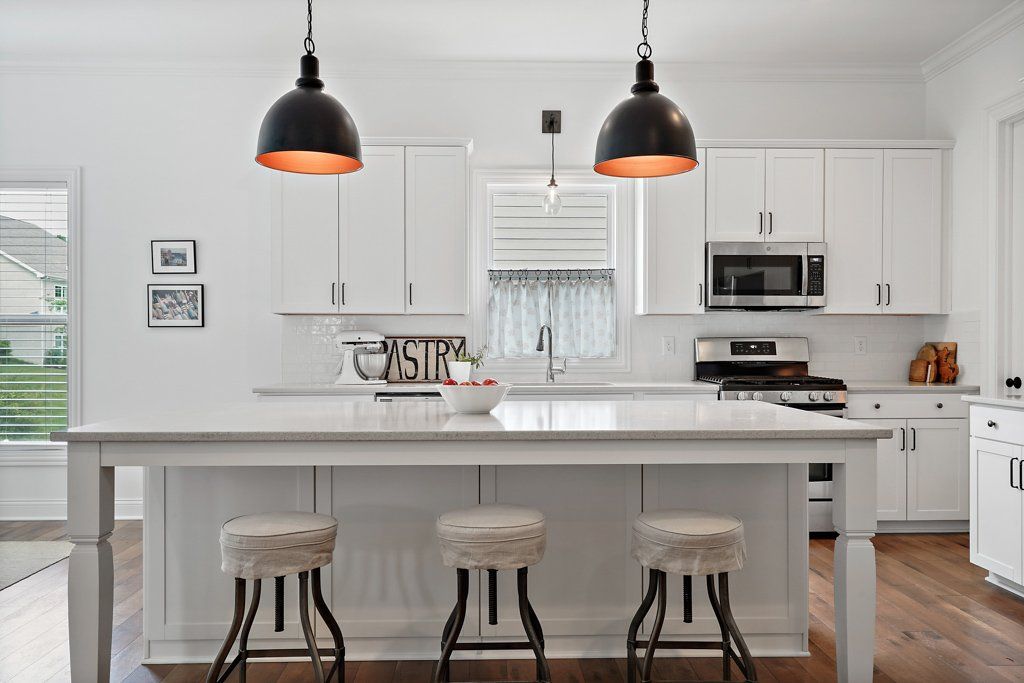 A kitchen with white cabinets and stools and a large island
