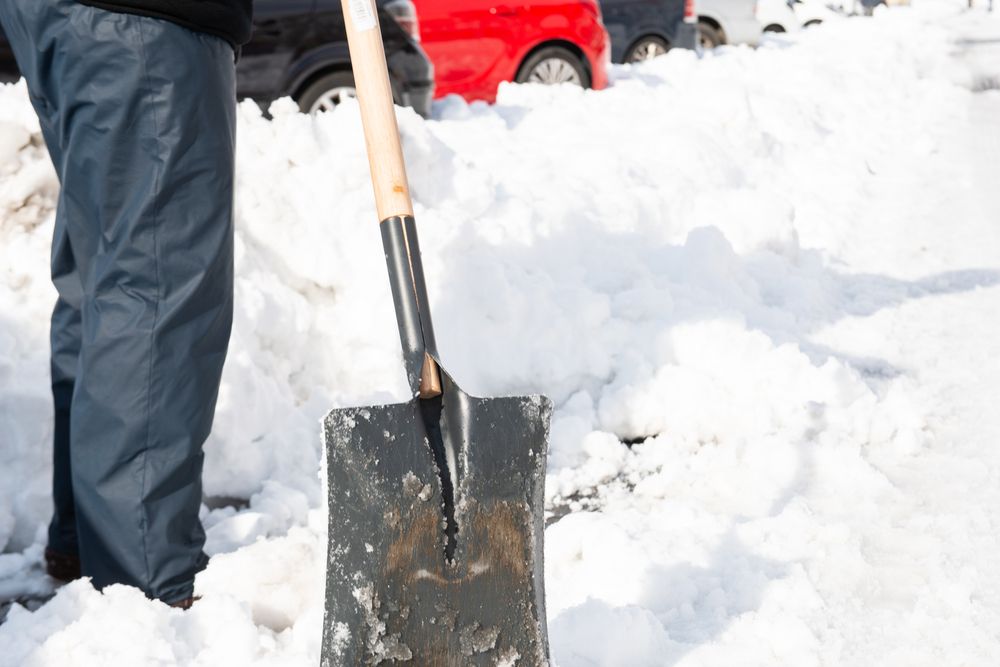 Person shoveling snow on a snowy day; shovel in the foreground.