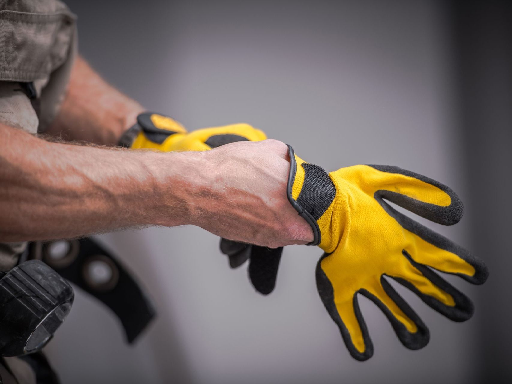 Person putting on yellow and black work gloves.