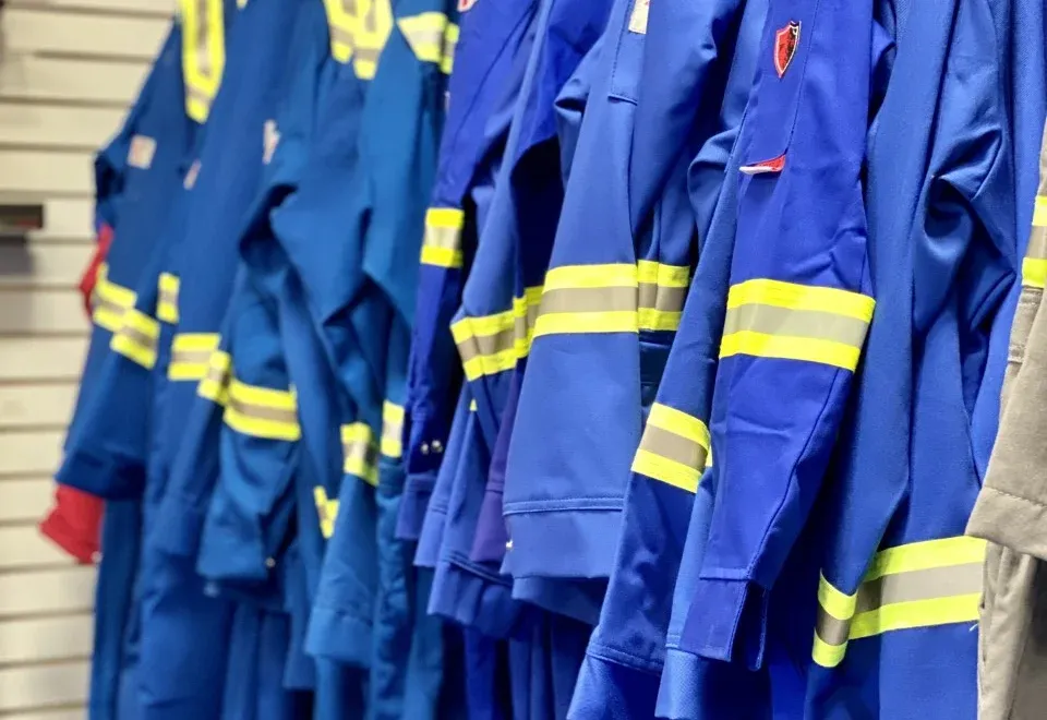 Blue work coveralls with reflective stripes hanging on a rack.