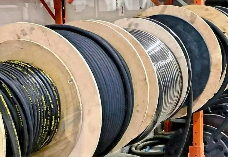 Spools of thick black electrical cable on wooden spools, stored on shelves.