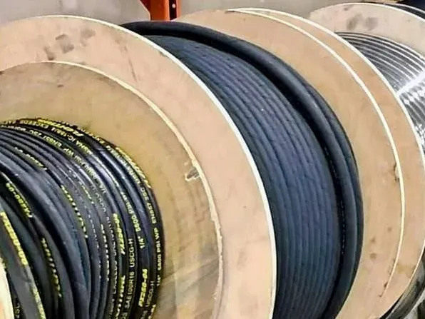 Spools of black electrical cable, wood and metal reels, industrial storage.