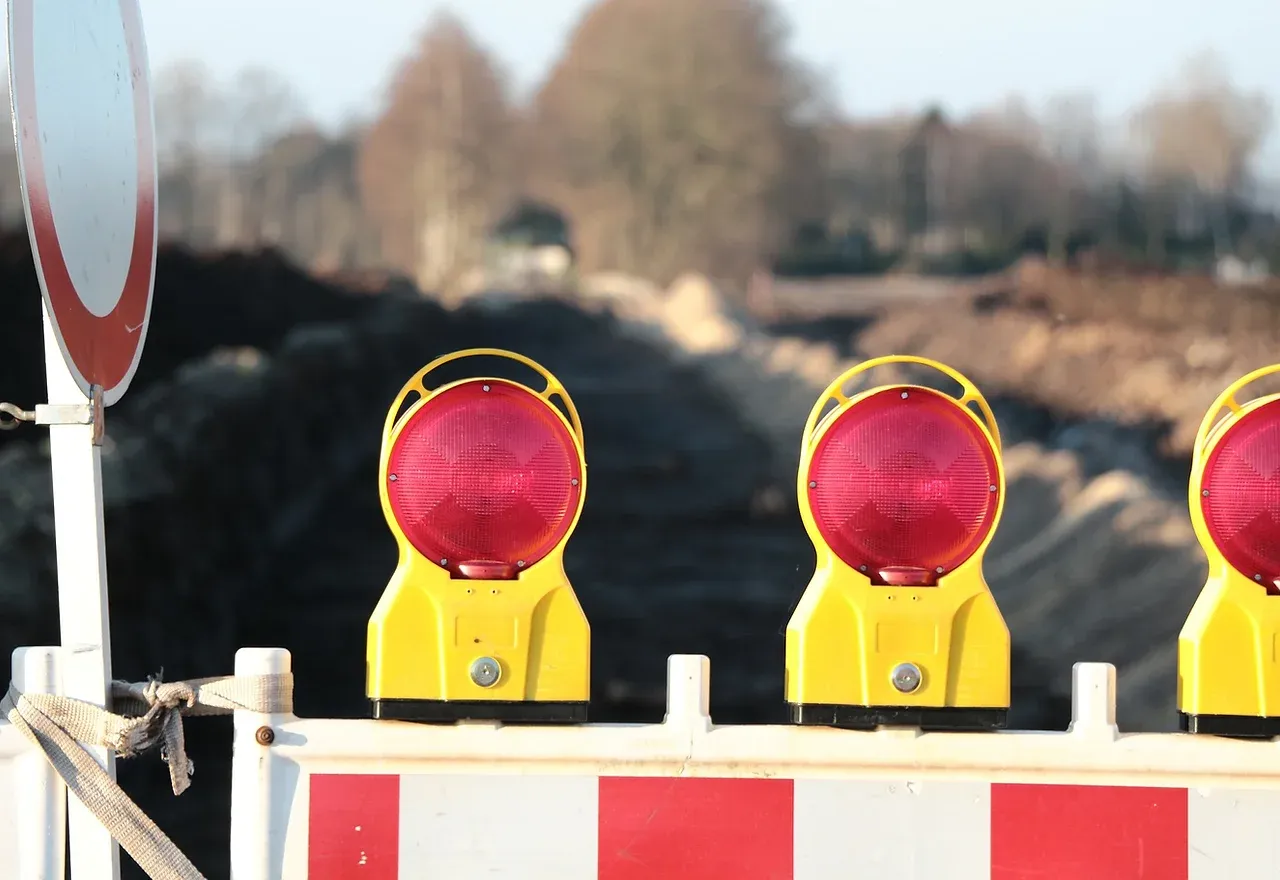 Road construction site with red flashing warning lights.