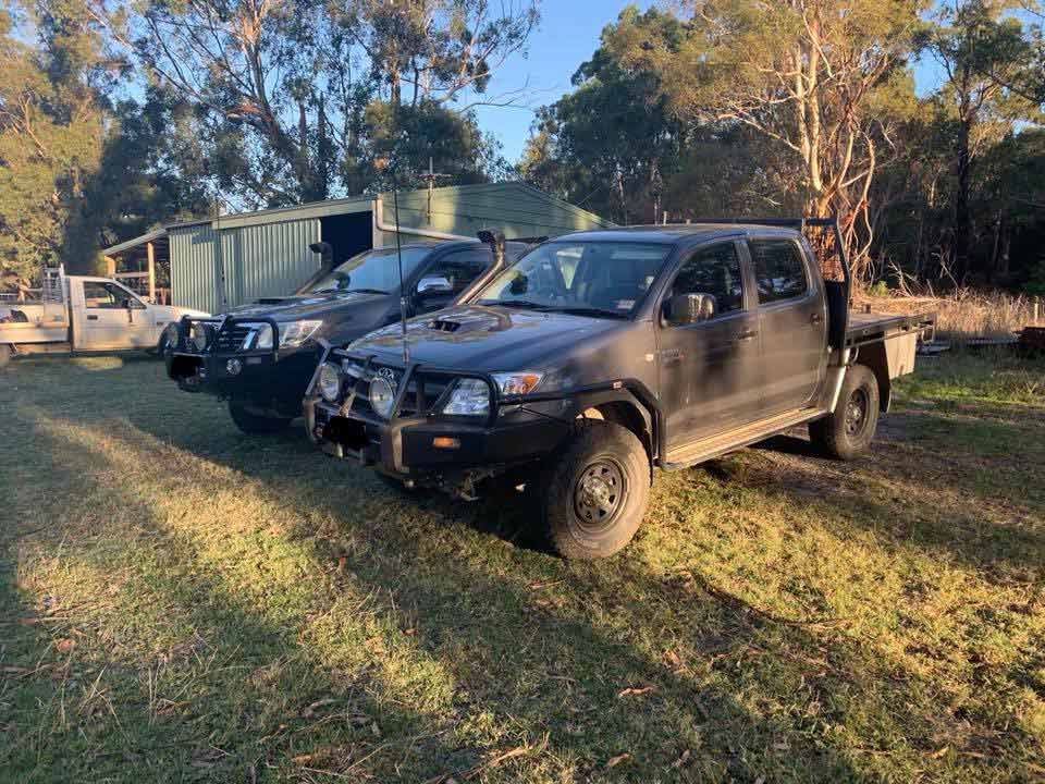 Two Trucks Are Parked Next To Each Other In A Grassy Field — Dieselflash Whitsundays in Airlie Beach, QLD