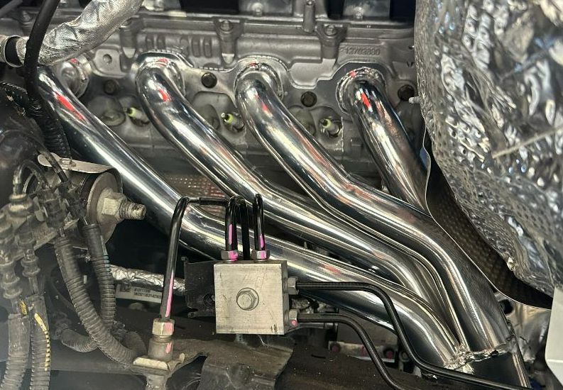 A Close Up of a Stainless Steel Exhaust Pipe on a Car Engine — Dieselflash Whitsundays in Proserpine, QLD