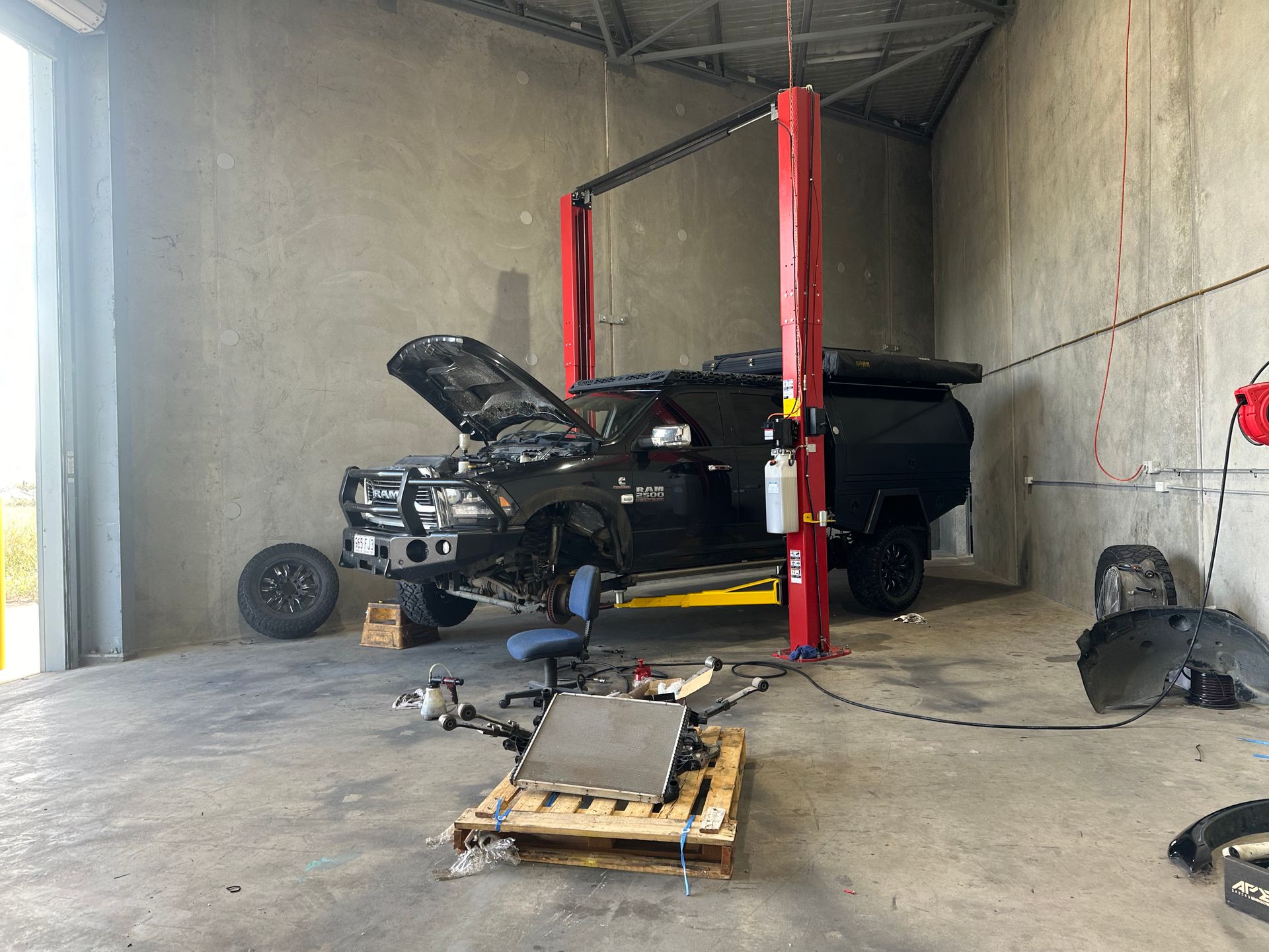 A Truck is Sitting on a Lift in a Garage With Its Hood Open — Dieselflash Whitsundays in Bowen, QLD