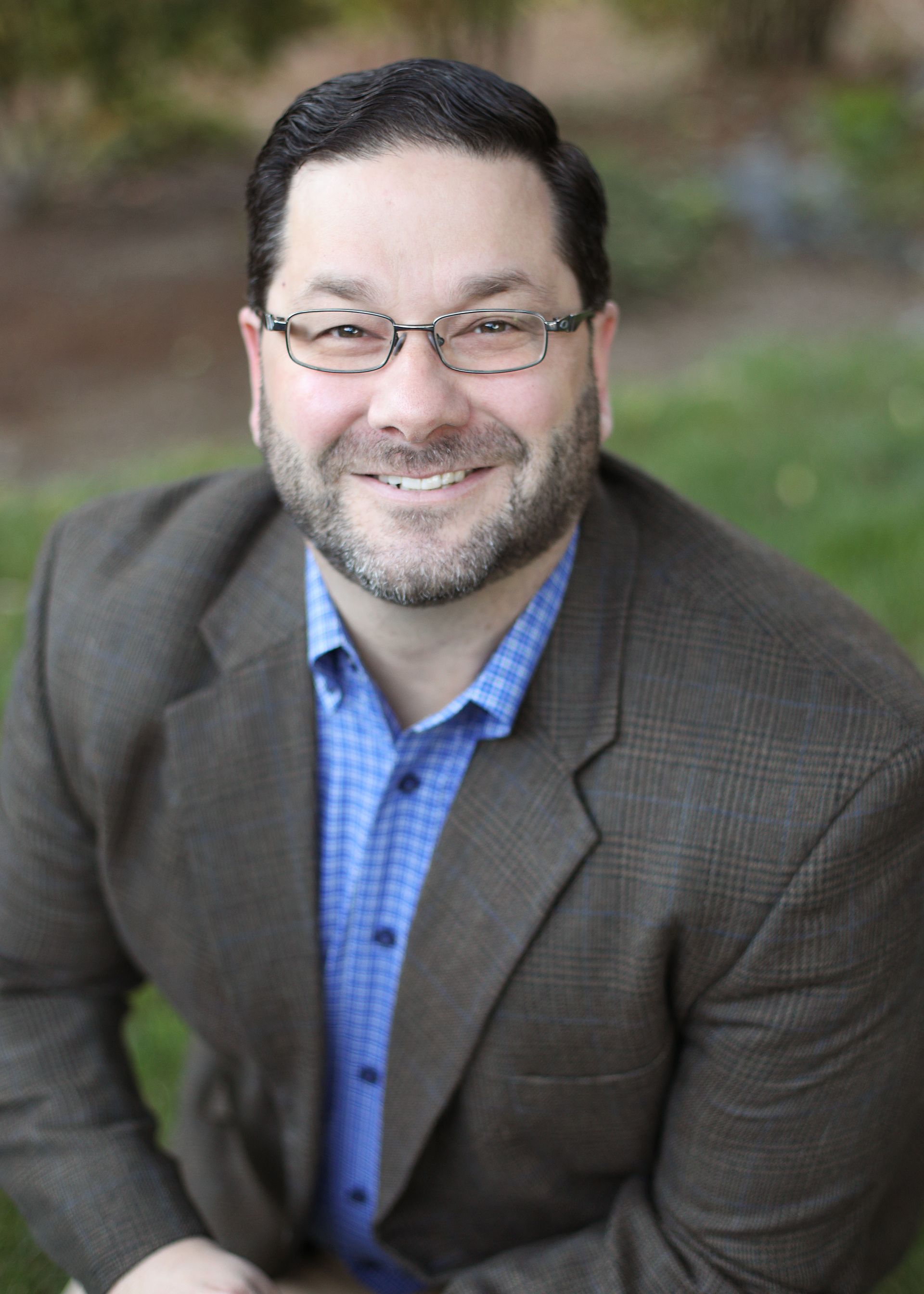 A man in a suit and glasses is smiling for the camera.