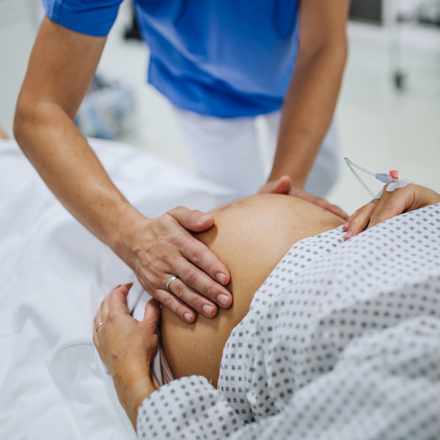 A nurse is giving a pregnant woman a massage in a hospital bed.