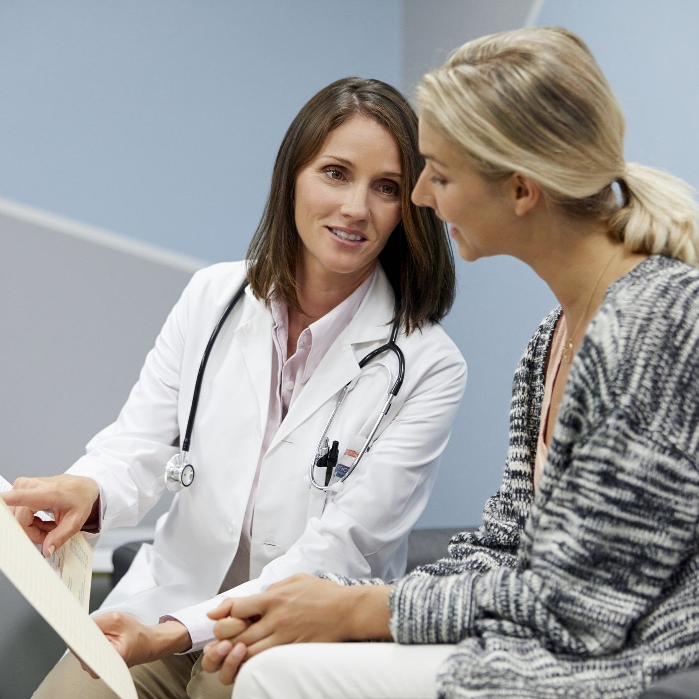A doctor is talking to a patient who is sitting on a couch
