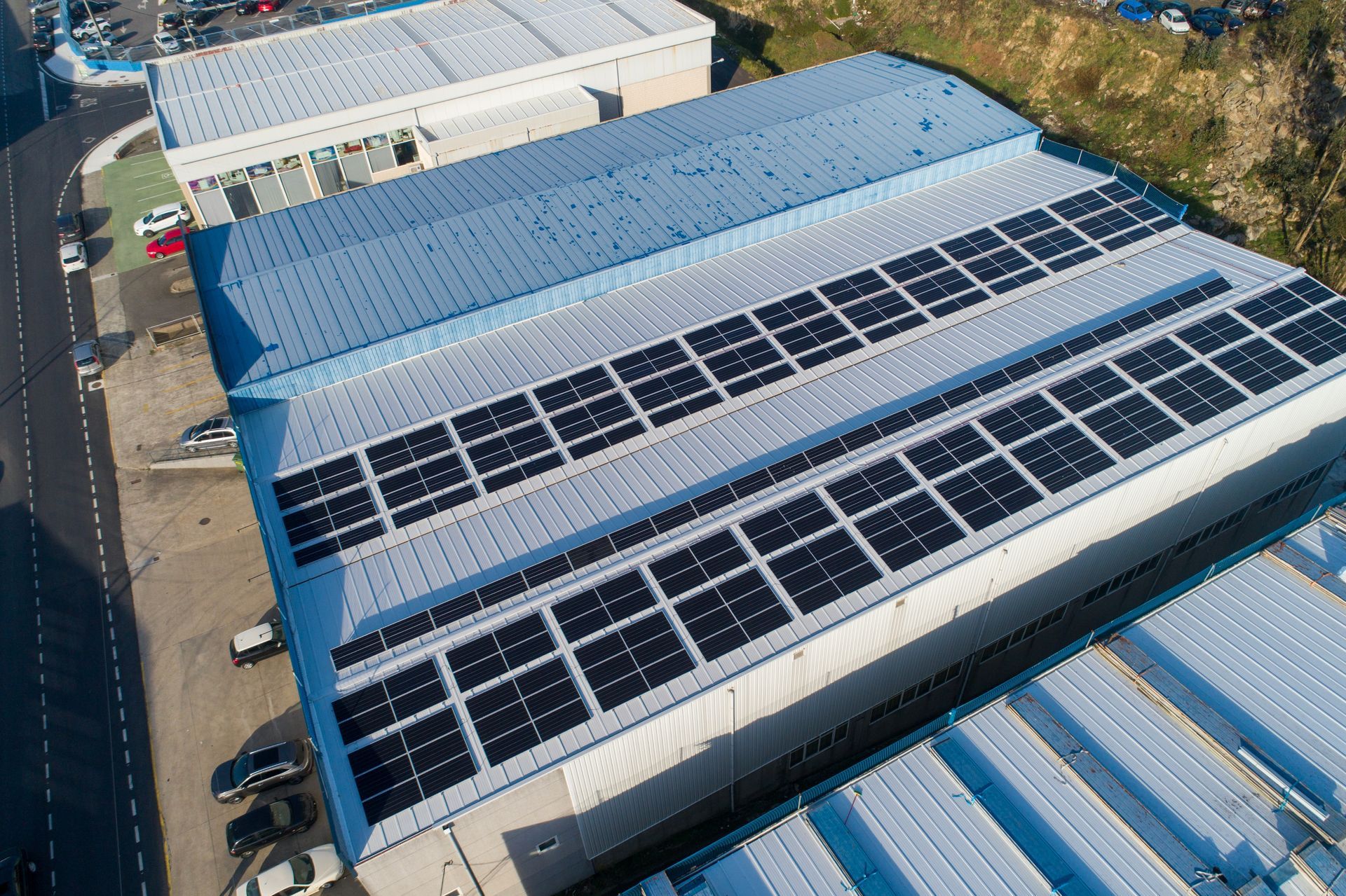 Aerial view of a blue industrial roof covered with solar panels