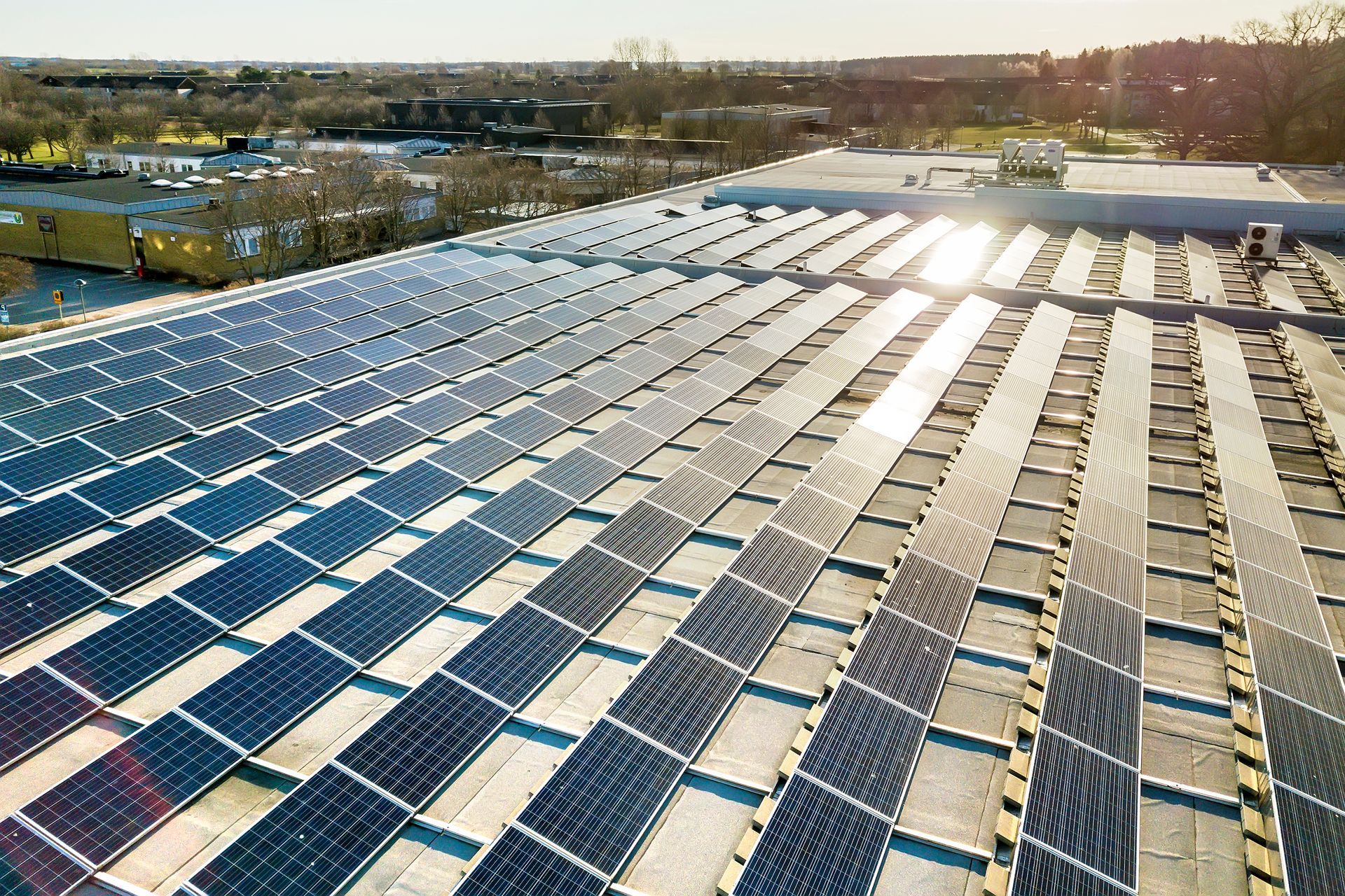 Aerial view of rows of blue solar panels on a rooftop at sunrise