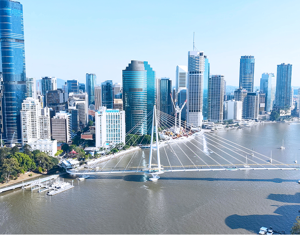 City skyline with a cable-stayed bridge over a wide river on a clear day