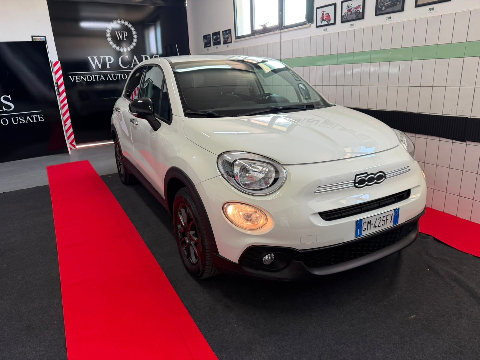 SUV Opel Mokka bianco parcheggiato in uno showroom con interni neri e rossi.