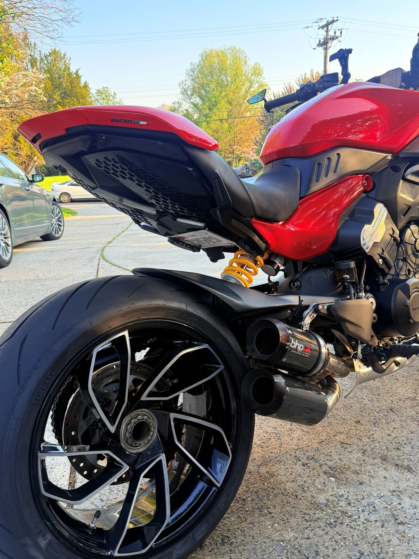 Red sport motorcycle with black rear wheel parked on a sunny street