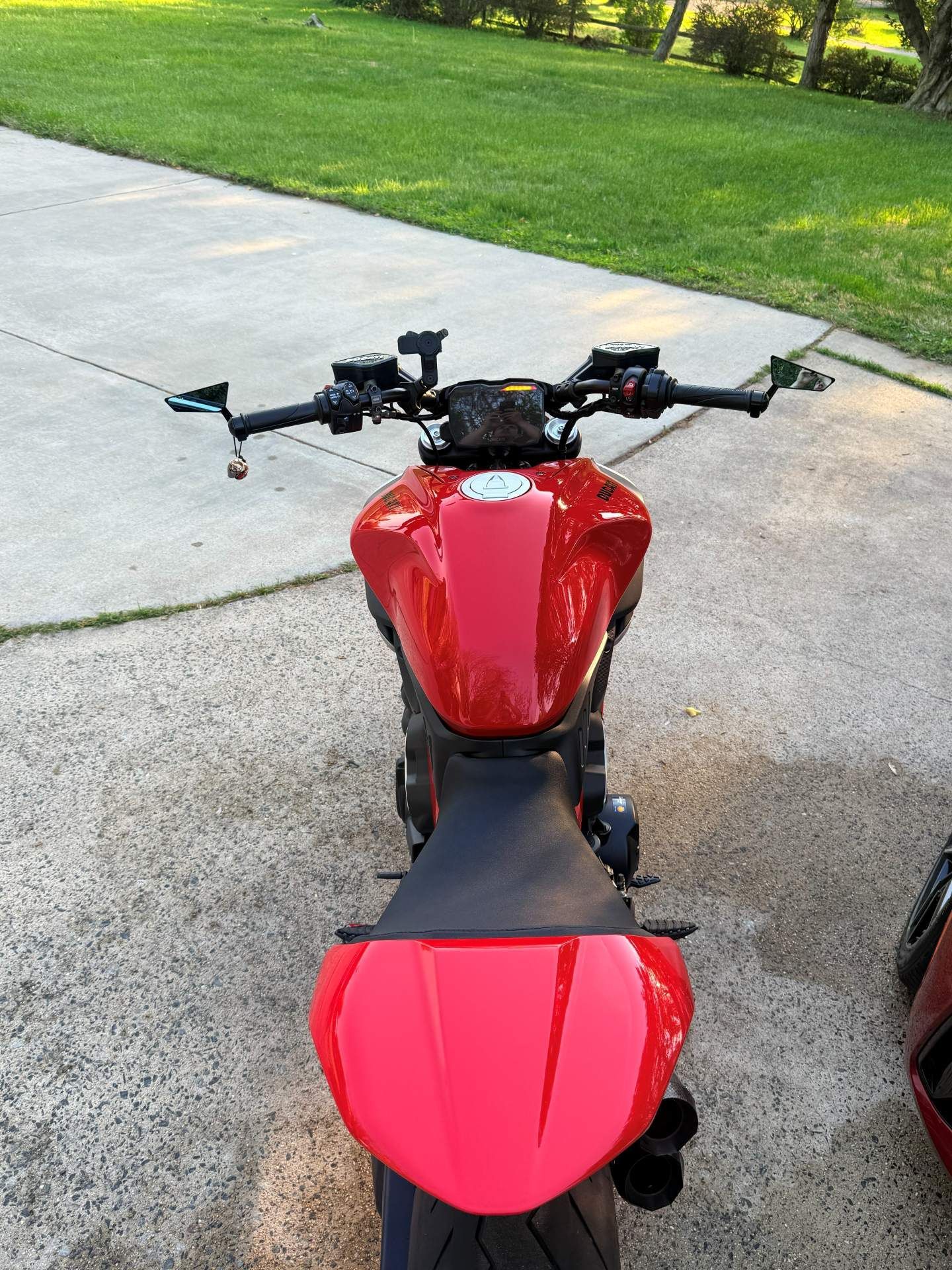 Red sport motorcycle parked on a driveway, viewed from above the seat and handlebars.