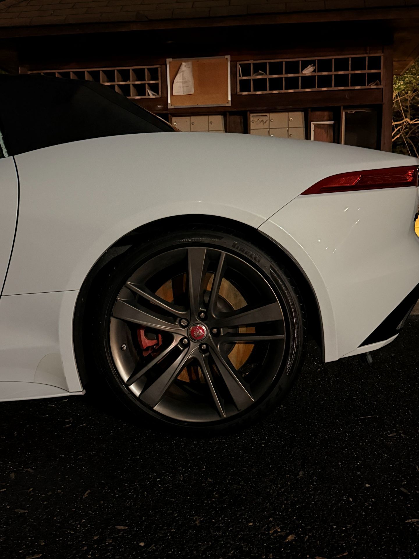 White sports car rear wheel parked at night in a driveway or garage.