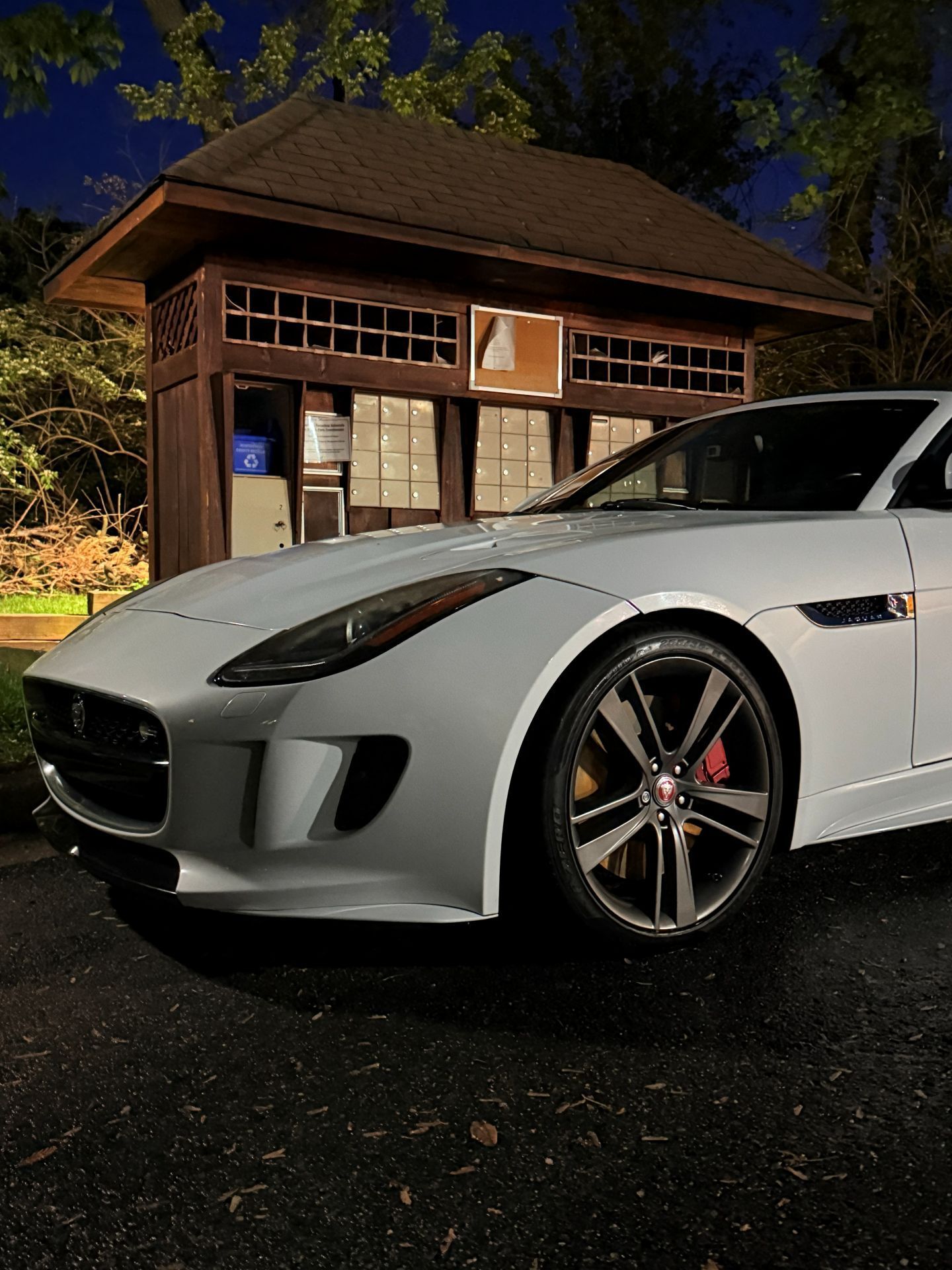 White sports car parked at night in front of a lit wooden building