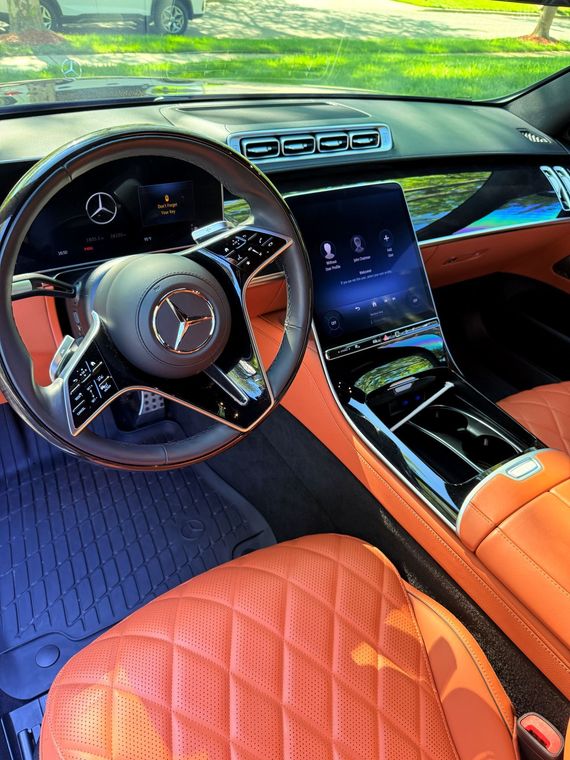 Luxury sports car interior with tan leather seats, digital dashboard, and carbon fiber trim.