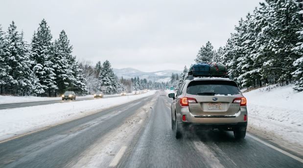 SUV driving on a snowy road with snow-covered trees and oncoming cars in winter.