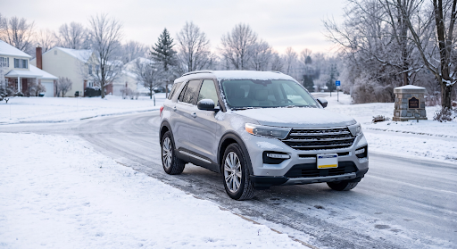 Silver SUV driving on a snowy residential street in winter
