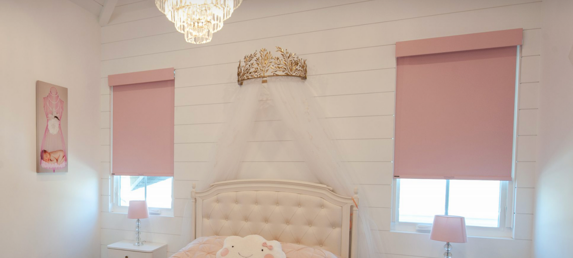 a bedroom with a bed , two windows and a chandelier and roller shades All Window Decor (817) 448-3393.
