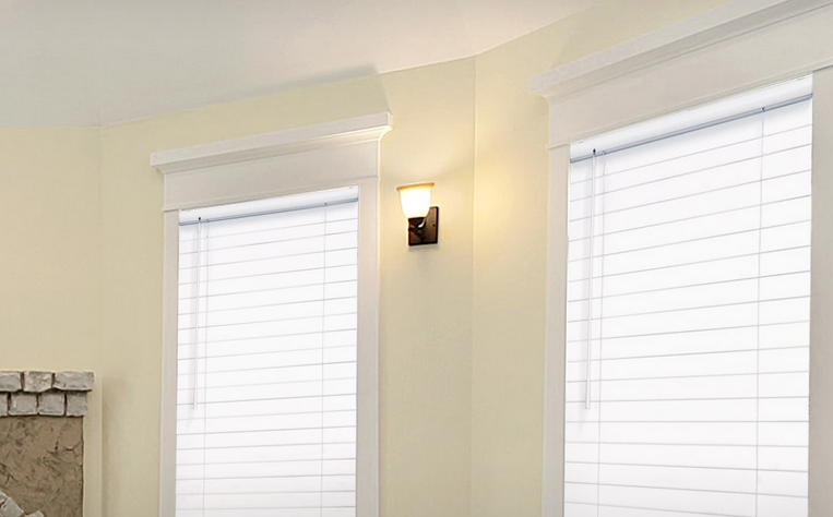 a bedroom with white faux wood blinds and a lamp on the wall All Window Decor (817) 448-3393.