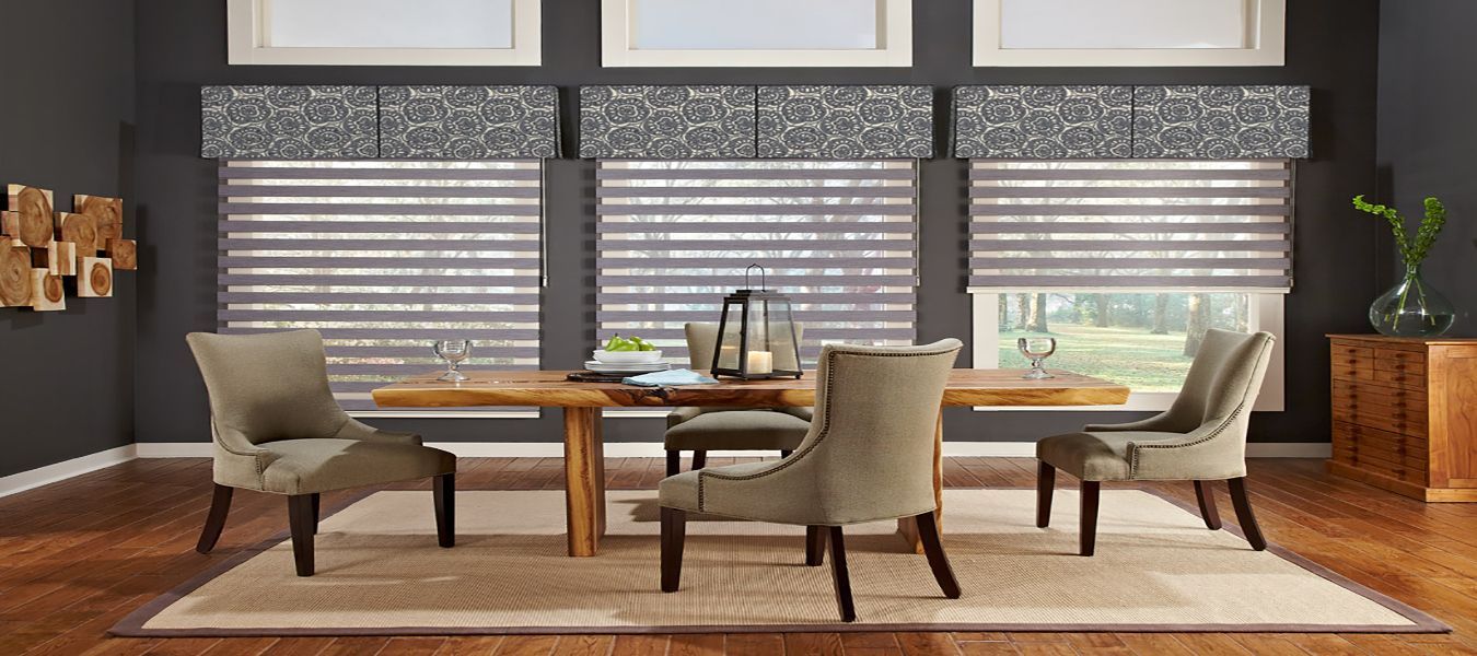 A dining room with a table and chairs and a rug and transitional shades on the windows All Window Decor (817) 448-3393 .