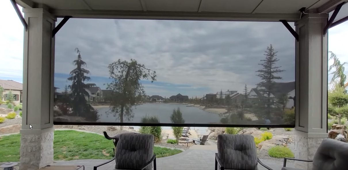 a screened in porch with chairs and a view of a lake with exterior patio shades All Window Decor (817) 448-3393.