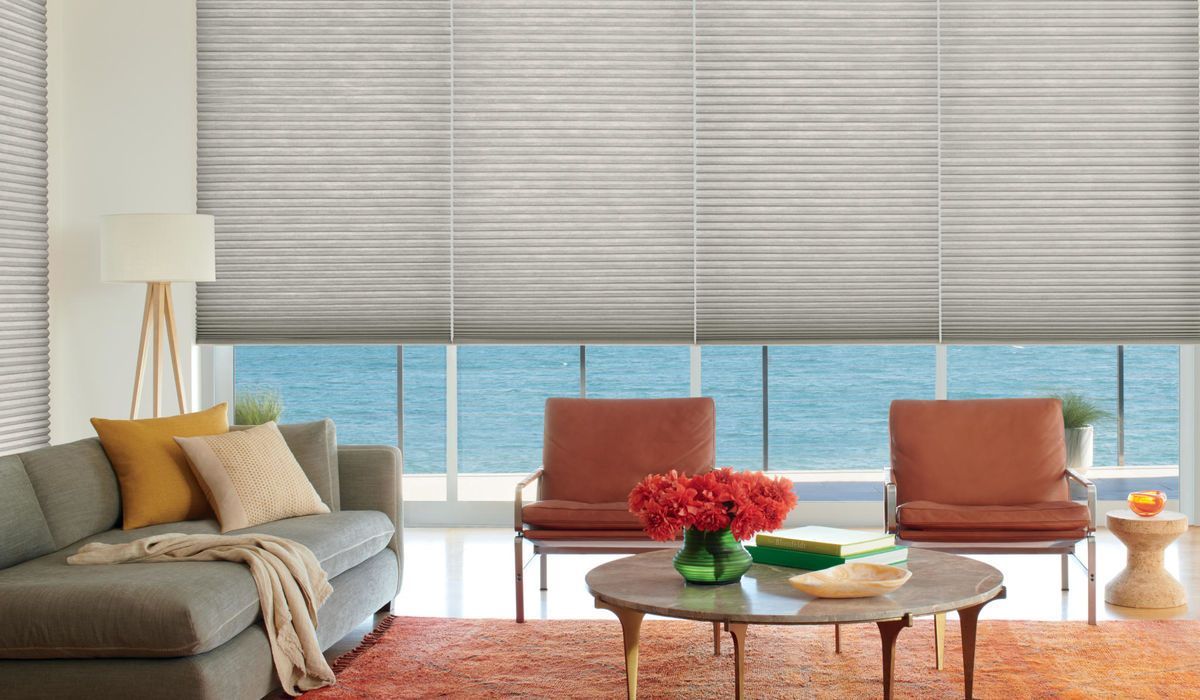 a living room with a couch , chairs , a table and a view of the ocean with honeycomb-shades  All Window Decor (817) 448-3393.