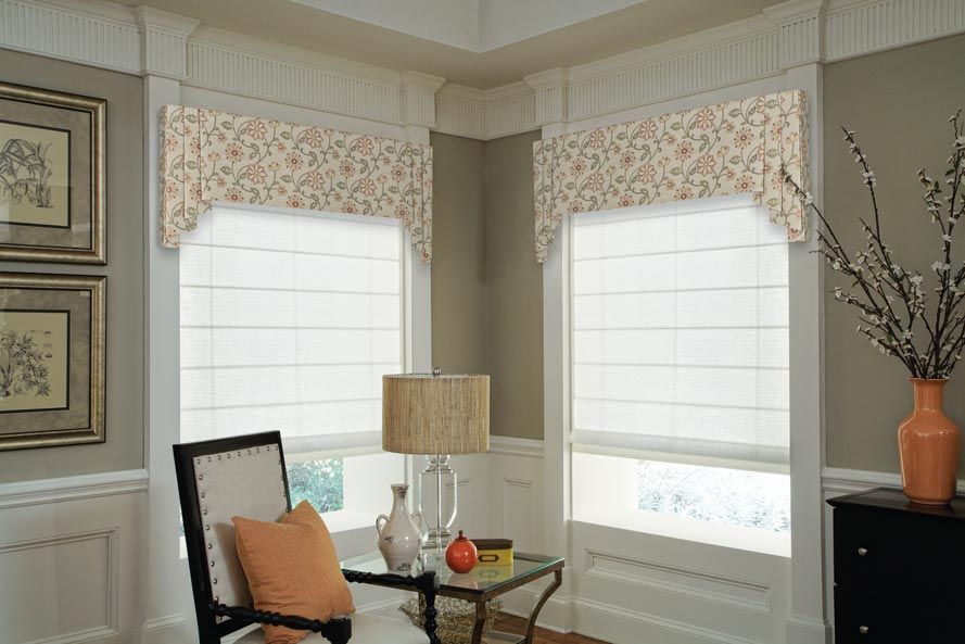 a living room with a chair , table , lamp and a vase of flowers with valances All Window Decor (817) 448-3393.