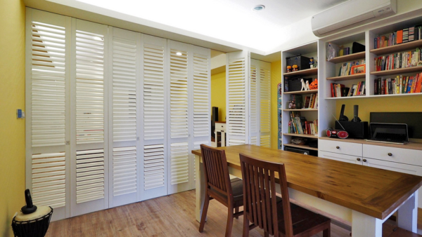 a dining room with a wooden table and chairs and shutters on the doors All Window Decor (817) 448-3393.