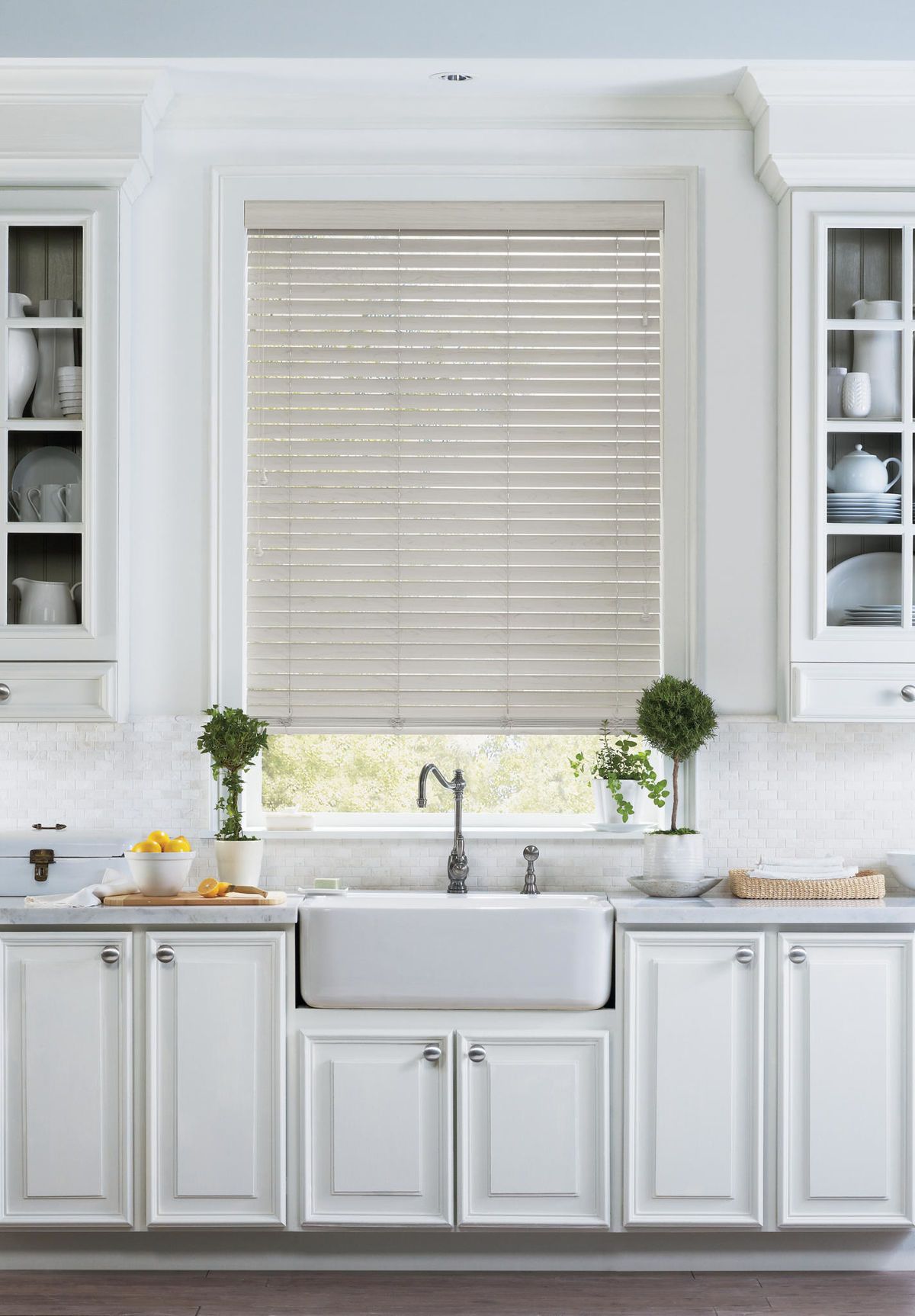 a kitchen with white cabinets , a sink , and a window with real wood blinds All Window Decor (817) 448-3393.