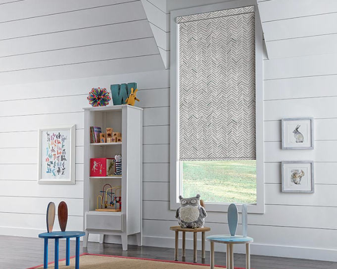 a child 's room with a bookshelf , chairs , and a window with roller shades All Window Decor (817) 448-3393.