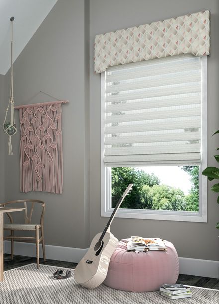 a room with a guitar sitting on a pink ottoman in front of a window with dual shades and a valance All Window Decor (817) 448-3393.