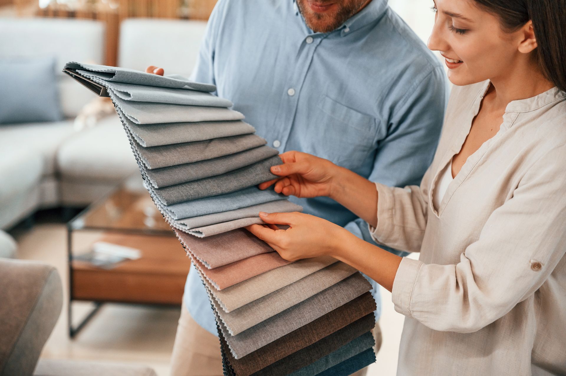 a man and a woman are looking at fabric samples in a living room All Window Decor (817) 448-3393.