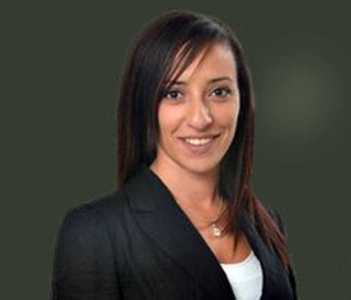 Portrait of a smiling person in a black blazer against a blue background