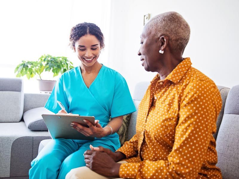 Two people sitting on a couch, smiling and looking at a tablet in a bright living room.