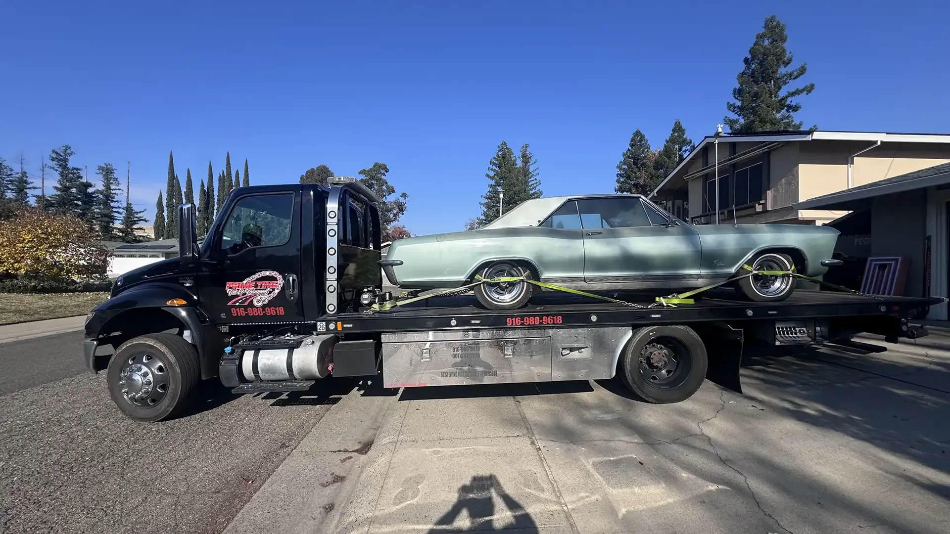 A tow truck is carrying a car on the back of it.