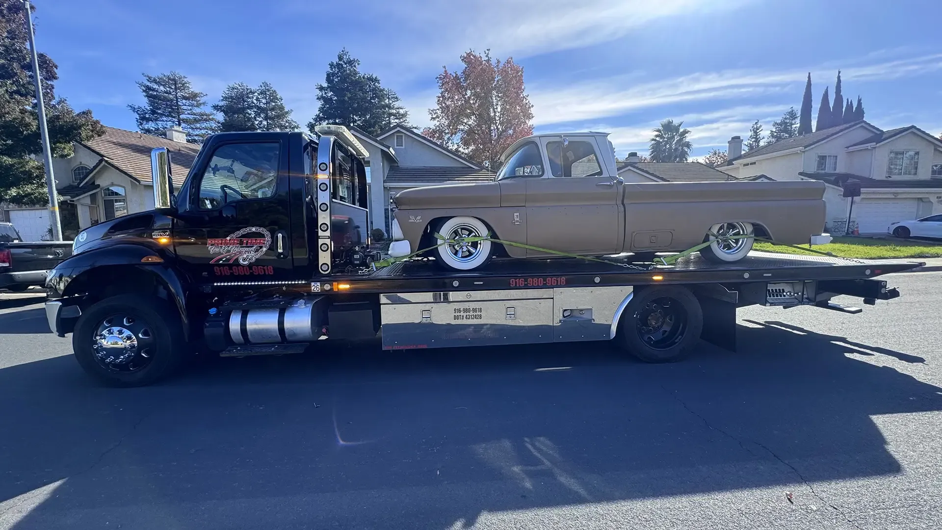 A tow truck is carrying a car on the back of it.