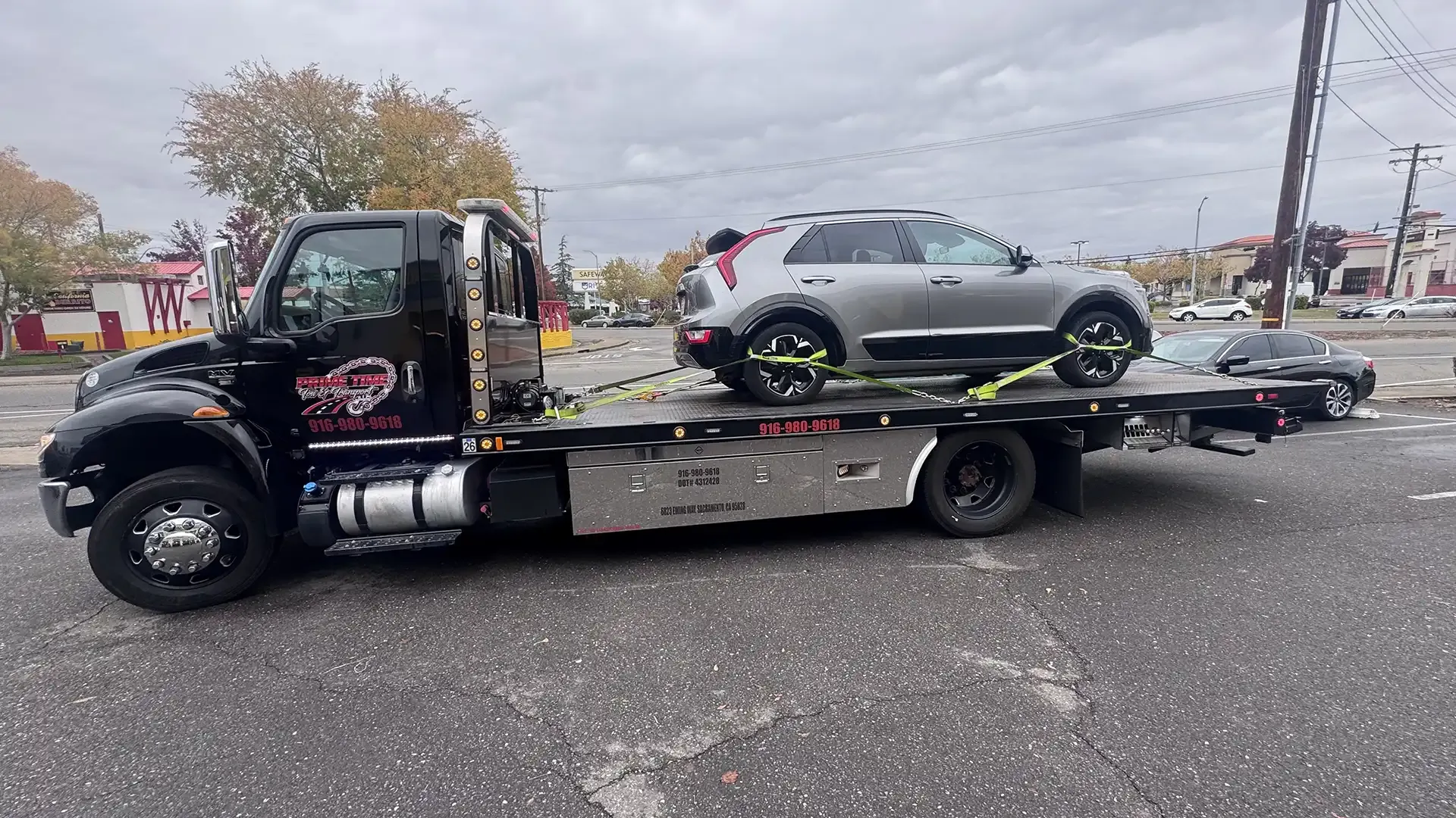 A tow truck is towing a car on the back of it.