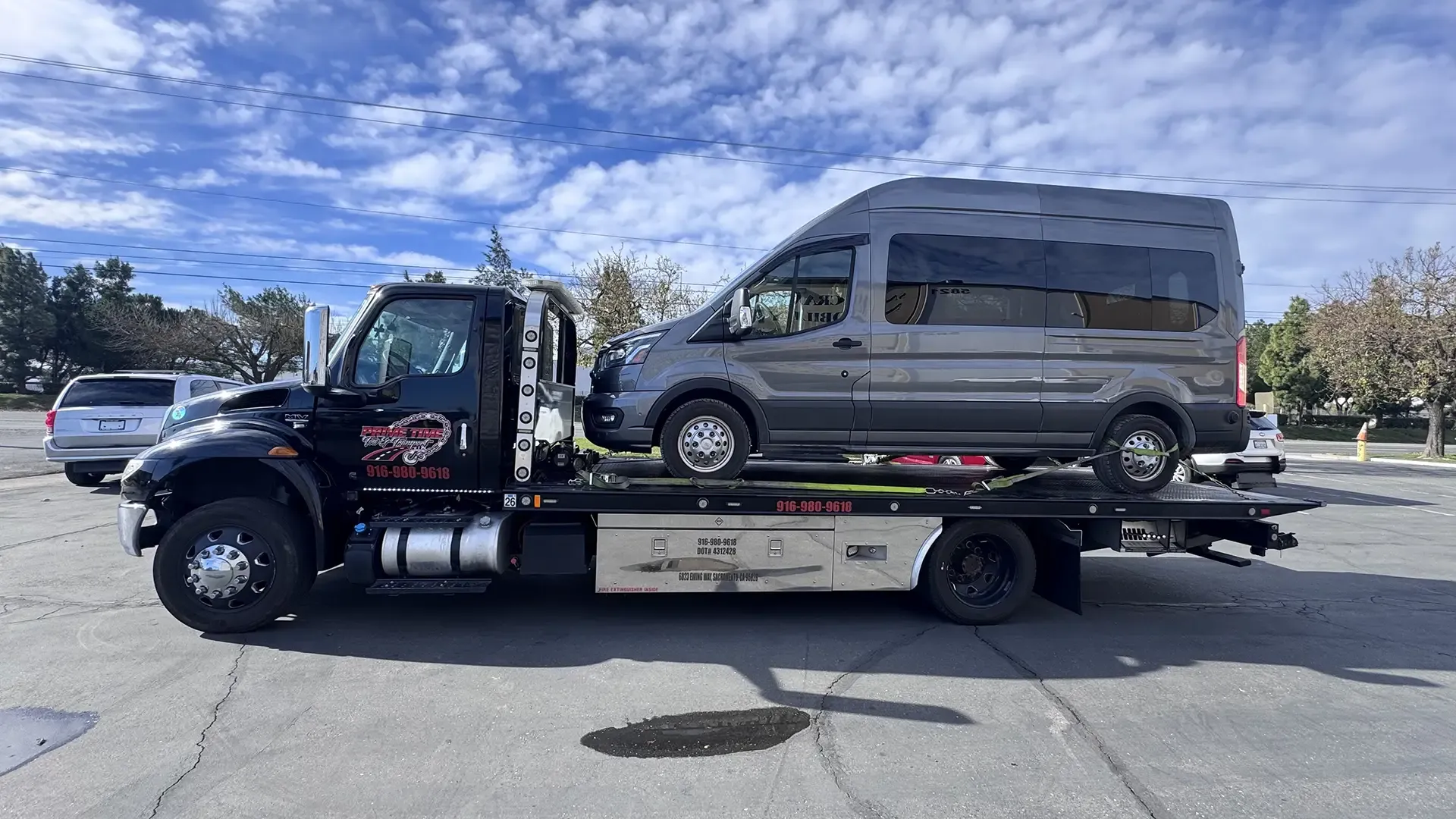 A tow truck is towing a van in a parking lot.