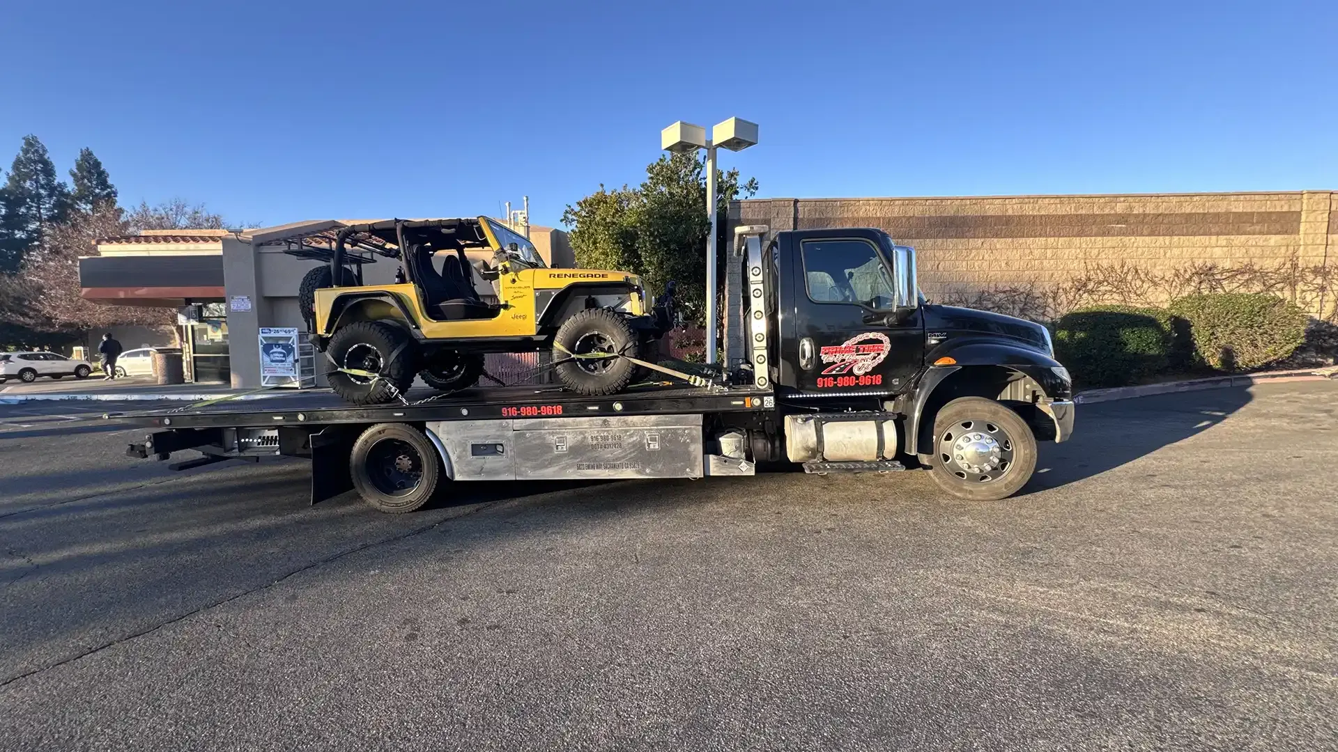 A yellow jeep is being towed by a tow truck.