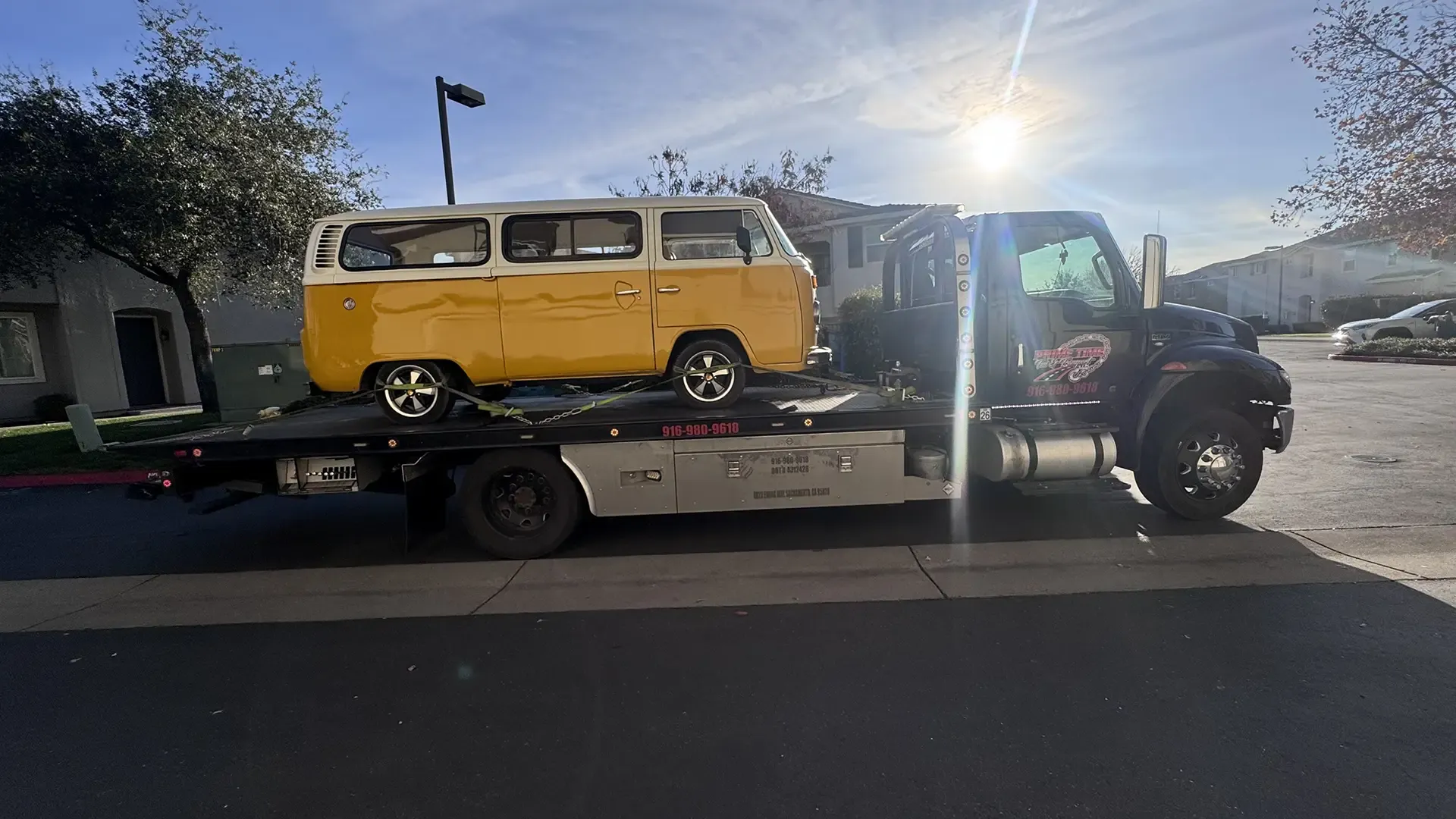 A yellow van is being towed by a tow truck.